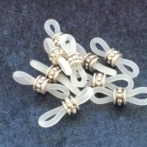 May include: A group of clear plastic eyeglass holders with silver metal beads. The holders are designed to keep glasses from sliding down the nose.