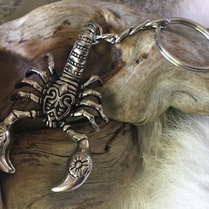 May include: Silver scorpion keychain with intricate details and a silver chain. The scorpion is posed with its tail raised and its claws extended.