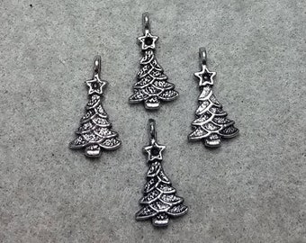 May include: Four silver Christmas tree charms with a star on top. The charms are detailed with a textured surface.