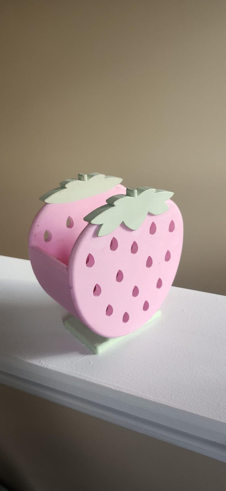 Peut inclure: Un plat en bois en forme de fraise rose et verte. Le plat a un motif d&eacute;coup&eacute; en forme de fraise avec des graines et des feuilles.