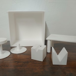 Puede incluir: Un conjunto de muebles en miniatura blancos, que incluye una mesa, dos taburetes, una caja y una pieza en forma de cuña. Los muebles están hechos de un material blanco liso y son perfectos para casas de muñecas o escenas en miniatura.