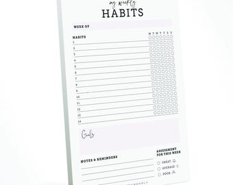 May include: A white notepad with the text "my weekly HABITS" at the top. The notepad includes sections for tracking habits, goals, notes, and a weekly assessment. The design is minimalist with black text and a simple layout.