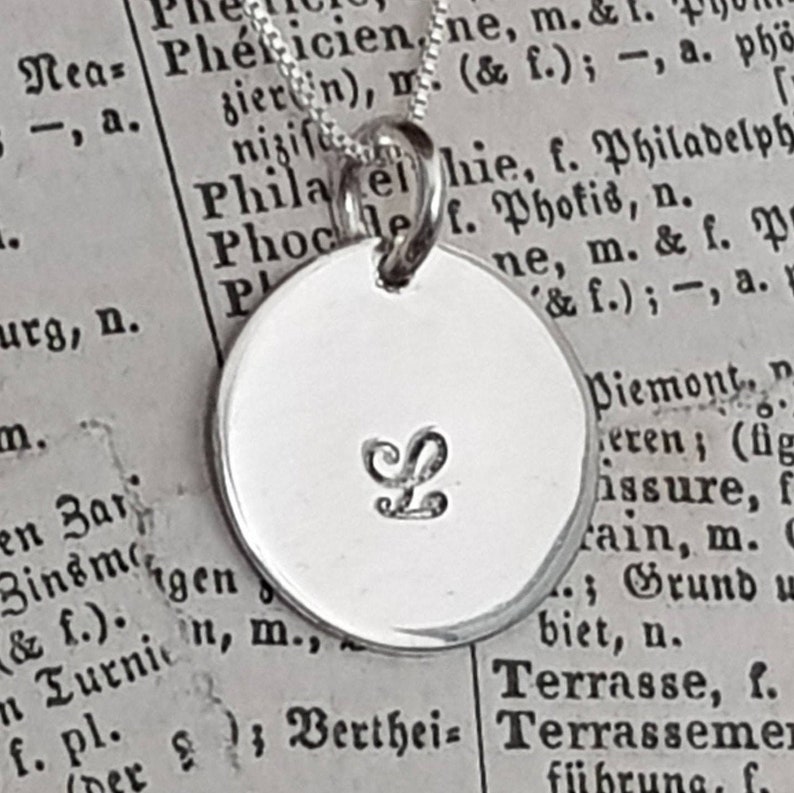 box chain necklace embellished by a personalized disc charm attached. available in sterling silver and gold-filled. necklace 16" or 18" or 20" long. the letter you have chosen is 3mm and hand stamped. the disc is 14.3mm 9/16"