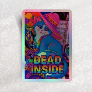 以下が含まれることがあります： ピンクのヒョウ柄の帽子をかぶった青い猫が描かれたホログラフィックステッカー。猫は虹色のネックレスをしており、「DEAD INSIDE」という言葉がカラフルなフォントで表示されています。背景には音符と花があります。