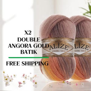 May include: Two skeins of Alize Angora Gold Batik yarn. The yarn is a blend of pink, peach, and yellow. The label reads "X2 DOUBLE ANGORA GOLD BATIK".