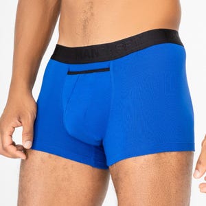 May include: Bright blue boxer briefs with a black waistband. The waistband features the text "MAN'S SET". The briefs have a small pocket detail on the front. The fabric appears to be a soft, stretchy material.