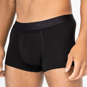 Könnte beinhalten: Schwarze Boxershorts mit bequemer Passform. Der Bund trägt das Wort „MAN'S“ in einem dezenten, geprägten Design. Die Unterwäsche hat einen klassischen, minimalistischen Stil.