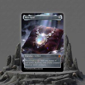 May include: A card featuring a detailed illustration of a necklace with a large, iridescent opal pendant. The card is labeled "Mox Opal" and includes text describing its "Metalcraft" ability. The background shows a dark, textured pillow.