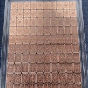 May include: A clear plastic package containing numerous small, copper-colored squares. Each square features a detailed spiderweb design. The squares are arranged in a grid pattern, creating a visually appealing and organized display.