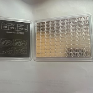 May include: A 100g silver CombiBar consisting of 100 individual 1g segments in a clear protective case. The black insert displays the text Silver 999, Weight 100 g, CombiBar, 100x1 g, and Certified assayer, along with four instructional diagrams.