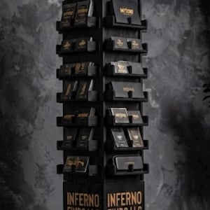 May include: A black wooden display stand with multiple shelves, showcasing various products. The stand features the word "INFERNO" in gold lettering at the top and the words "INFERNO FINDS LLC" at the base. The products appear to be black with gold accents.
