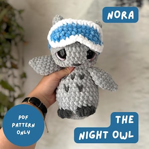 May include: A gray crocheted owl plush toy with large dark eyes and a blue and white striped headband. The text on the image reads NORA THE NIGHT OWL and PDF PATTERN ONLY. The owl has a textured, soft appearance with small dark gray feet.