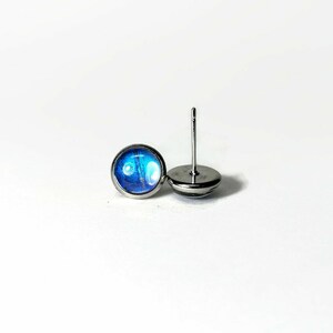 May include: A pair of silver stud earrings with blue and white iridescent glass inserts.