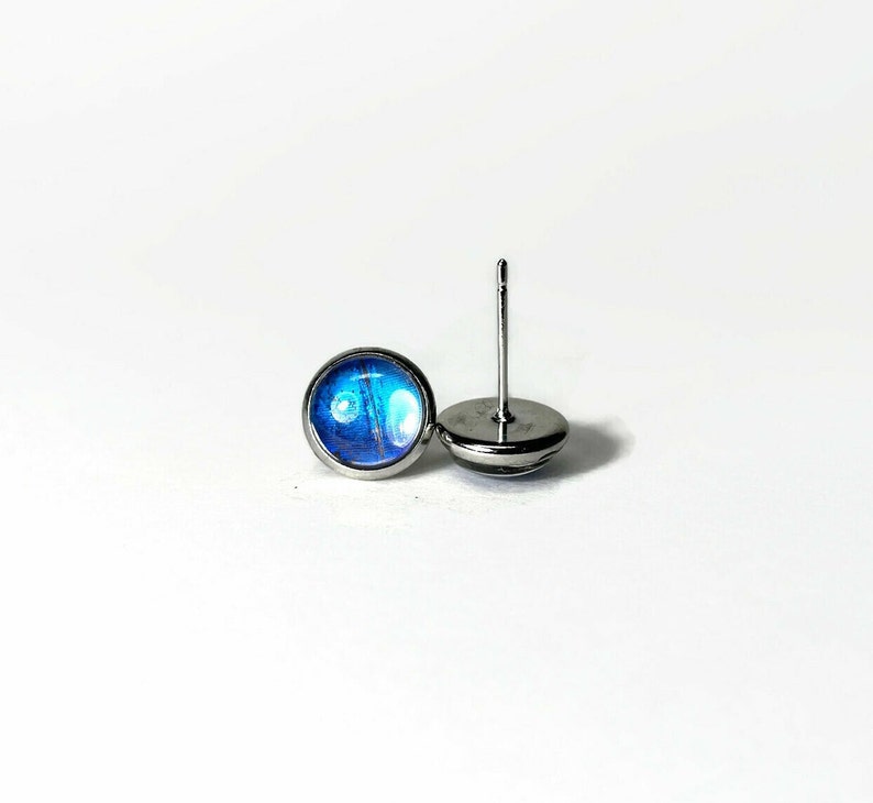 May include: A pair of silver stud earrings with blue and white iridescent glass inserts.