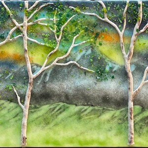 Puede incluir: Una obra de arte de mosaico de vidrio que representa un paisaje con dos abedules blancos en primer plano, follaje verde y una cordillera en el fondo. El cielo es un degradado de azul, verde, amarillo y naranja.