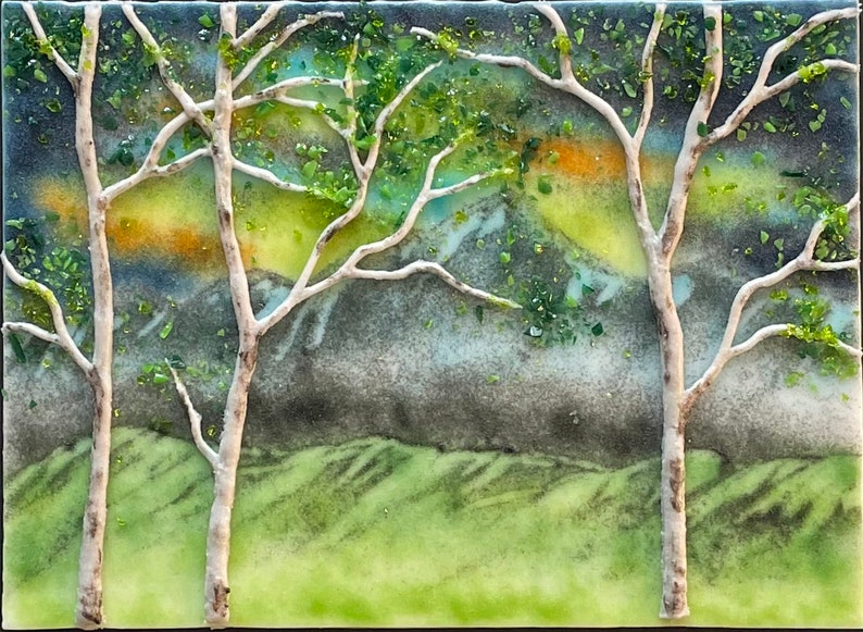 Puede incluir: Una obra de arte de mosaico de vidrio que representa un paisaje con dos abedules blancos en primer plano, follaje verde y una cordillera en el fondo. El cielo es un degradado de azul, verde, amarillo y naranja.