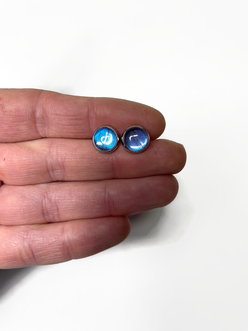 May include: A pair of silver stud earrings with blue and purple butterfly wing designs.