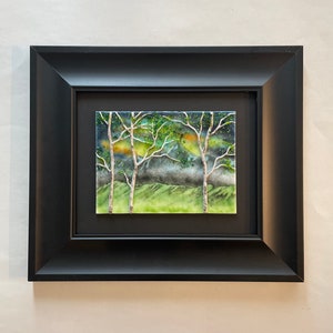 Puede incluir: Obra de arte enmarcada que presenta un azulejo de cer&aacute;mica con una escena de paisaje de tres &aacute;rboles con troncos blancos y hojas verdes sobre un fondo azul oscuro y verde.