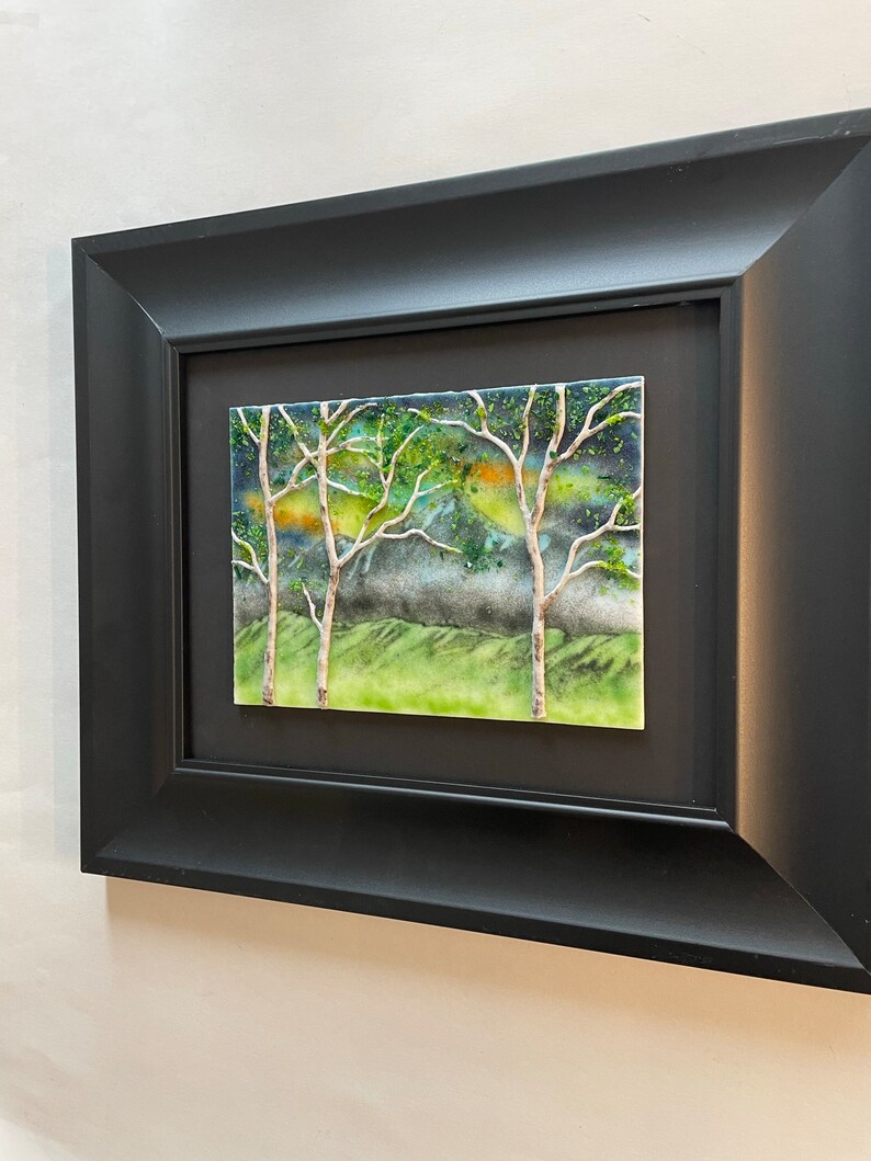 Puede incluir: Una obra de arte enmarcada que representa una escena de paisaje con &aacute;rboles y un cielo nublado. La obra est&aacute; hecha de azulejos de cer&aacute;mica y presenta un estilo texturizado y abstracto.