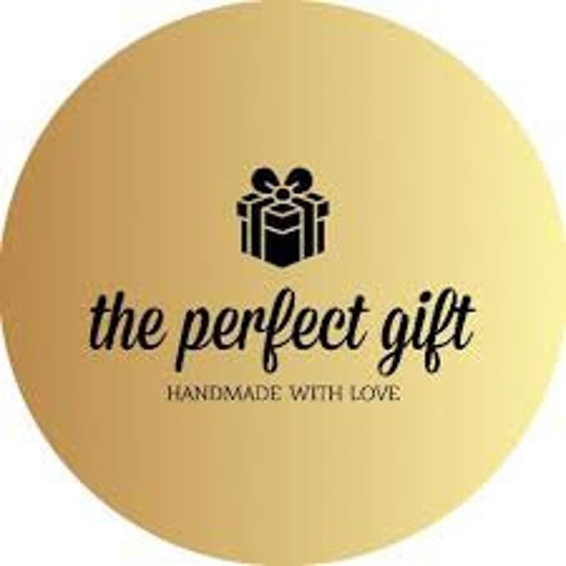 May include: A gold circle with a gradient effect. The circle features a black silhouette of a gift box with a bow on top. The text "the perfect gift" is written in black below the gift box. The text "handmade with love" is written in smaller black text below the first line of text.