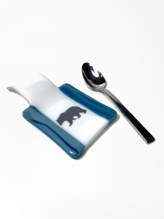 A fused-glass spoon rest shaped like a blue bear — a genuinely handcrafted, visually distinctive kitchen piece that doubles as art you actually use every day.