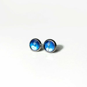 May include: A pair of silver stud earrings with blue and white butterfly wing designs.