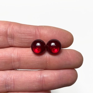 May include: Two round, red glass beads.