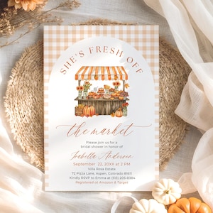 May include: A bridal shower invitation with a market theme. The invitation features a watercolour illustration of a market stall with pumpkins and flowers. The text reads "She's Fresh Off the Market". The invitation is surrounded by pumpkins and flowers.