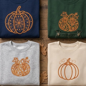 Può includere: Quattro felpe girocollo in blu navy, verde scuro, grigio melange e crema. Ognuna presenta un disegno di zucca ricamato in arancione sul petto. La felpa blu navy ha una zucca in stile mandala, le altre mostrano diverse illustrazioni di zucche.
