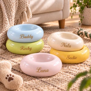 May include: Five round, smooth ceramic pet bowls in pastel colours including light blue, lime green, cream, yellow, and soft pink. Each bowl features a personalised name engraved in gold script: Buddy, Rocky, Nala, Sadie, and Luna.