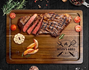 May include: A wooden cutting board with a grilled steak, sliced to reveal the pink interior. Garnishes include tomatoes, garlic, and potato wedges. The board is branded with "Deven's Grill".