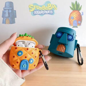 Op de afbeelding: Oranje ananasvormige AirPod-hoes met groene bovenkant en blauwe deur. Een teal-kleurige kopvormige hoes staat ernaast. De afbeelding bevat ook een cartoonafbeelding van een ananashuis, een stenen hoofd en de tekst "SpongeBob SquarePants".