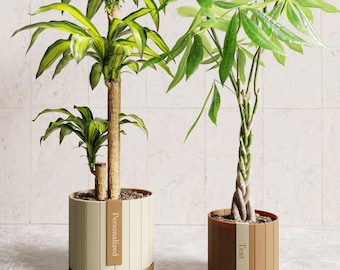May include: Two cylindrical plant pots with vertical slats. The left pot is cream-colored with a brown vertical label reading "Personalized". The right pot is brown with a cream-colored vertical label reading "Text". Each pot contains a green plant.