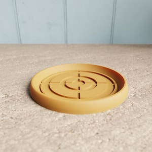 May include: A round, terracotta-colored plant saucer with a raised center and concentric circle design. The saucer has a diameter of approximately 6 inches and is made of a durable material. Ideal for indoor or outdoor use.