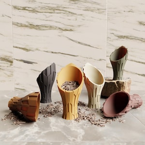 May include: A collection of six decorative, cone-shaped vases in various colors, including brown, black, yellow, and green. The vases have a textured, geometric design and are filled with small, brown pieces. Some vases are upright, while others are lying on their sides.