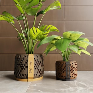 May include: A white ceramic mug with a black handle and the text "But First, Coffee" in a bold, black font. The mug is filled with a dark liquid, likely coffee, and sits on a light-colored surface.