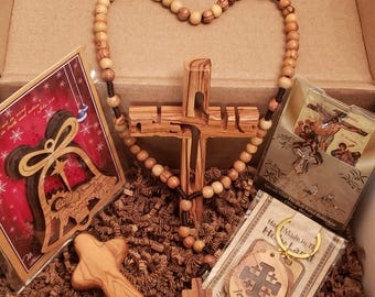 May include: A collection of religious items, including a wooden cross, rosary, and keychains, presented in a box. The cross is intricately carved, and the rosary beads form a heart shape. The keychains feature a Jerusalem cross design.