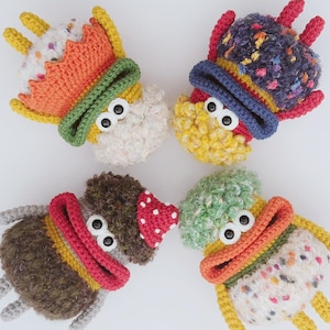 May include: Four whimsical, handmade crochet creatures with large googly eyes. Each has a unique color scheme, including orange, green, yellow, and brown, with textured yarn and playful details. These soft sculptures are perfect for children's toys or decorative accents.