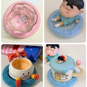 May include: A collection of handmade crochet coasters in pink and blue, featuring a clear glass bowl, a small cartoon character figurine, a ceramic cup with a red bow, and a ceramic mug with a blue lid and a small character topper.