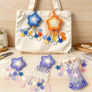 May include: A cream-colored canvas tote bag adorned with two large crocheted star ornaments in blue and orange, featuring dangling smaller stars. Below, three additional crocheted star accessories are displayed, including two star-shaped motifs and one star-patterned net pouch in shades of purple, blue, and white.