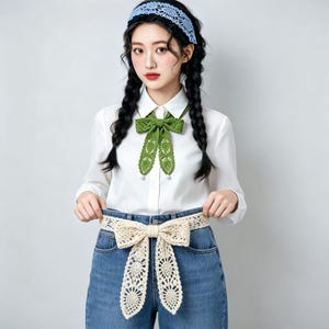 May include: A light blue crochet headband, a white long-sleeved button-down shirt, a green crochet bow tie with small white beads at the ends, and a cream-colored crochet belt tied in a bow around blue denim jeans with a visible button and zipper.
