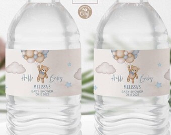 May include: Two clear water bottles with labels for a baby shower. The labels feature a teddy bear holding balloons, clouds, and the text "Hello Baby." The text "Melissa's Baby Shower 08.15.2022" is also included. The bottles are on a white surface.
