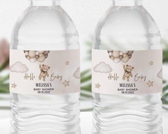 May include: Two clear water bottles with labels featuring a teddy bear holding balloons, clouds, and stars. The labels read "Hello Baby" and "Melissa's Baby Shower 08.15.2022". The text "Search: 05V1 for matching items" is at the top.
