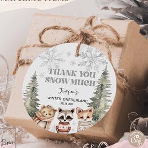 May include: A gift box wrapped in brown paper and tied with twine, featuring a round tag. The tag reads "Thank You Snow Much" with winter-themed illustrations of a hedgehog, raccoon, and fox. The text "Jackson's Winter Onederland Dec 20, 2088" is also present.