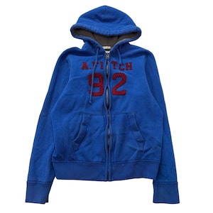 May include: A bright blue zip-up hoodie featuring a dark red embroidered logo that reads A.FITCH 92 on the chest. The garment includes a drawstring hood with a grey interior lining, long sleeves with ribbed cuffs, a ribbed hem, and two front pockets.