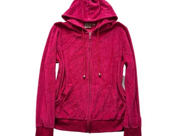 May include: A vibrant fuchsia zip-up hoodie with a hood and front pockets. The hoodie features a full-length zipper, matching drawstrings, and ribbed cuffs and hem. The fabric has a soft, textured appearance.