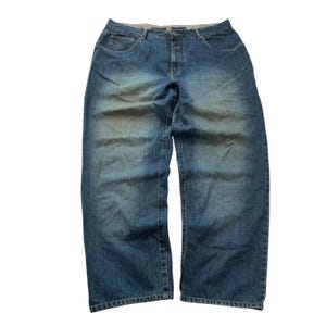 May include: Blue denim jeans featuring a relaxed, wide-leg fit with a faded wash effect on the thighs. The pants include a standard button and zipper fly closure, two front pockets, and a coin pocket, finished with visible stitching throughout.