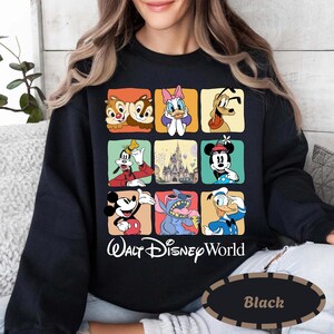 May include: Black sweatshirt featuring a grid of Disney characters including Chip and Dale, Daisy Duck, Pluto, Goofy, Mickey Mouse, Stitch, and Donald Duck. The words "Walt Disney World" are printed below the grid in white script.