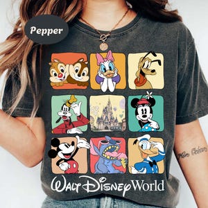 May include: Dark gray t-shirt featuring a grid of Disney characters including Chip and Dale, Daisy Duck, Pluto, Goofy, Mickey Mouse, Stitch, and Donald Duck. The words "Walt Disney World" are printed at the bottom.