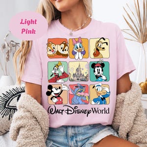 May include: Light pink t-shirt featuring a grid of Disney characters including Chip and Dale, Daisy Duck, Pluto, Goofy, Mickey Mouse, Stitch, and Donald Duck. The words "Walt Disney World" are printed in a script font at the bottom.